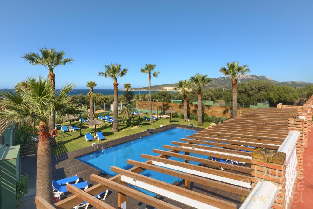 a view of the pool at a resort with palm trees at Dulce Nombre Hotel - Apartamentos in Tarifa