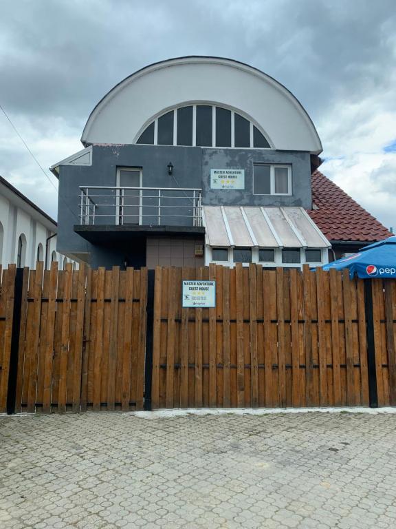 a house behind a wooden fence with a building at Master Adventure Guest House in Vadul lui Carol II