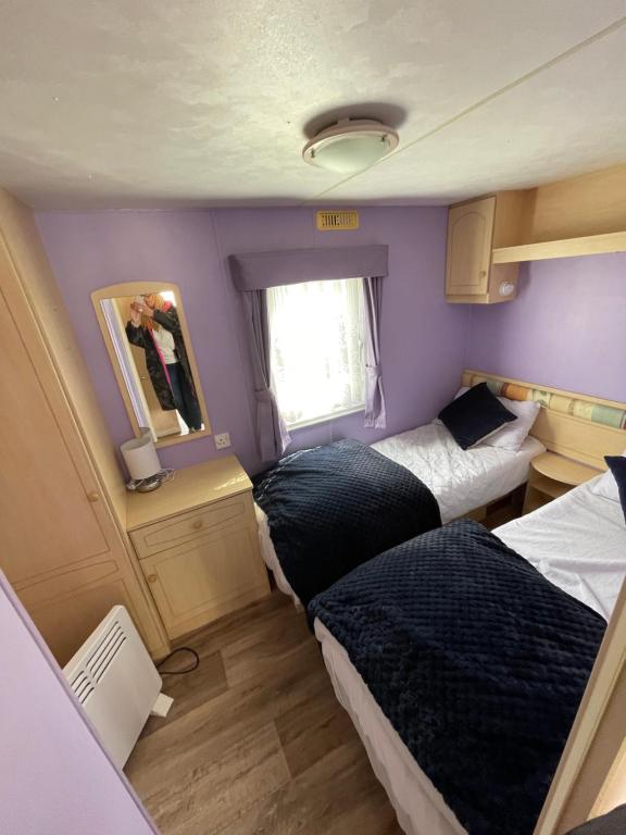 Charming 6 birth caravan in skegness في سكيجنيس: سريرين في غرفة صغيرة مع جدران أرجوانية