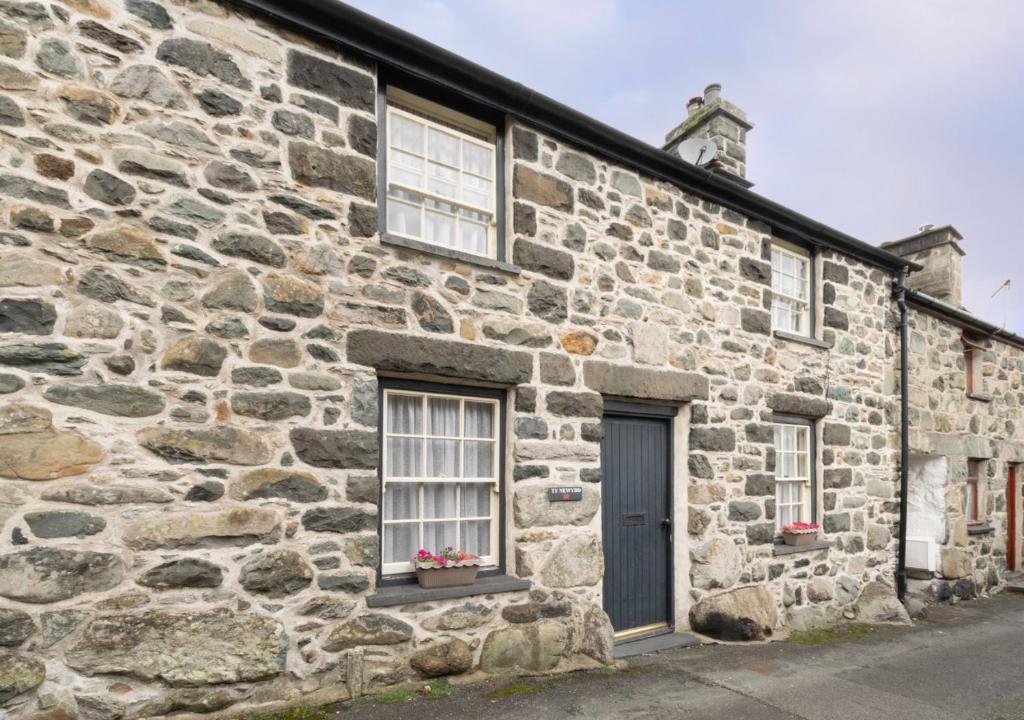 an old stone building with two windows and a door at Ty Newydd in Dolgellau