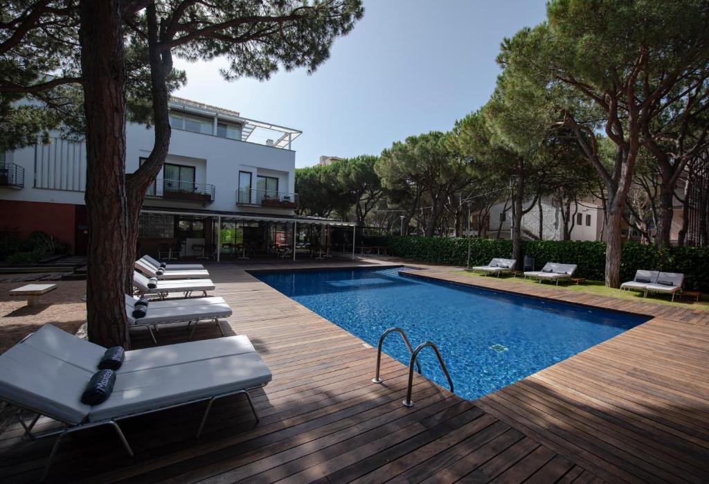 a swimming pool with lounge chairs next to a building at NM Suites by Escampa Hotels in Platja  d'Aro