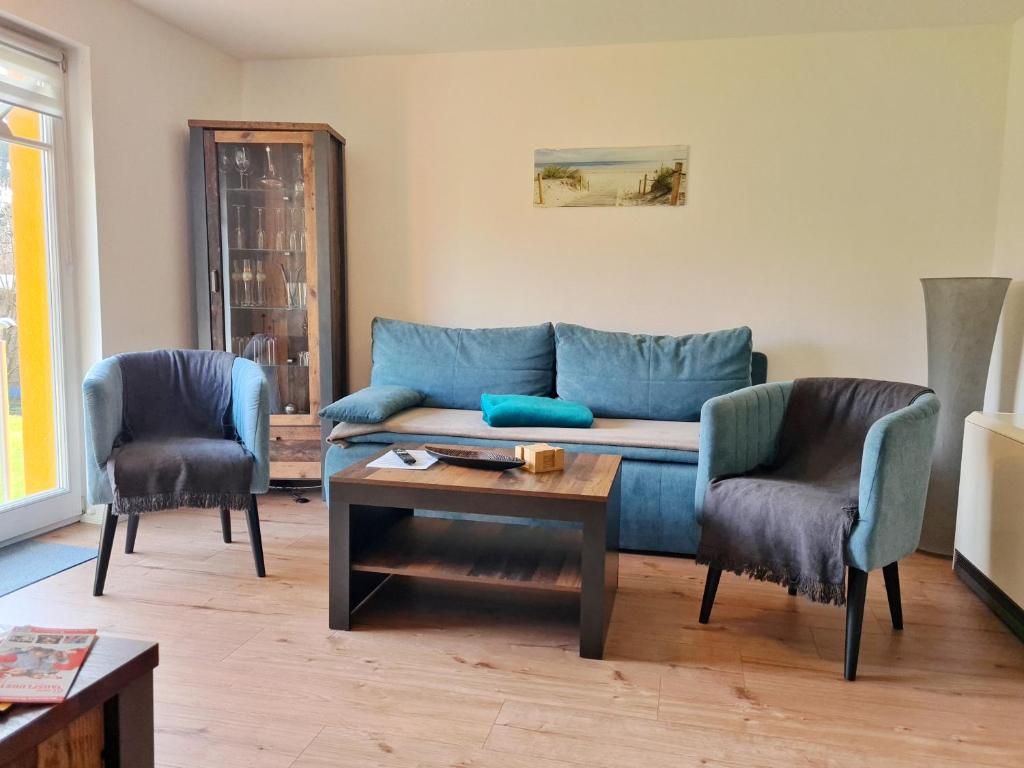 a living room with a blue couch and two chairs at Ferienwohnung Sandra in Barth