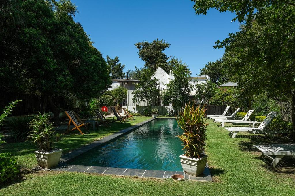 a swimming pool in a yard with lounge chairs and trees at Old Potters Inn in Greyton