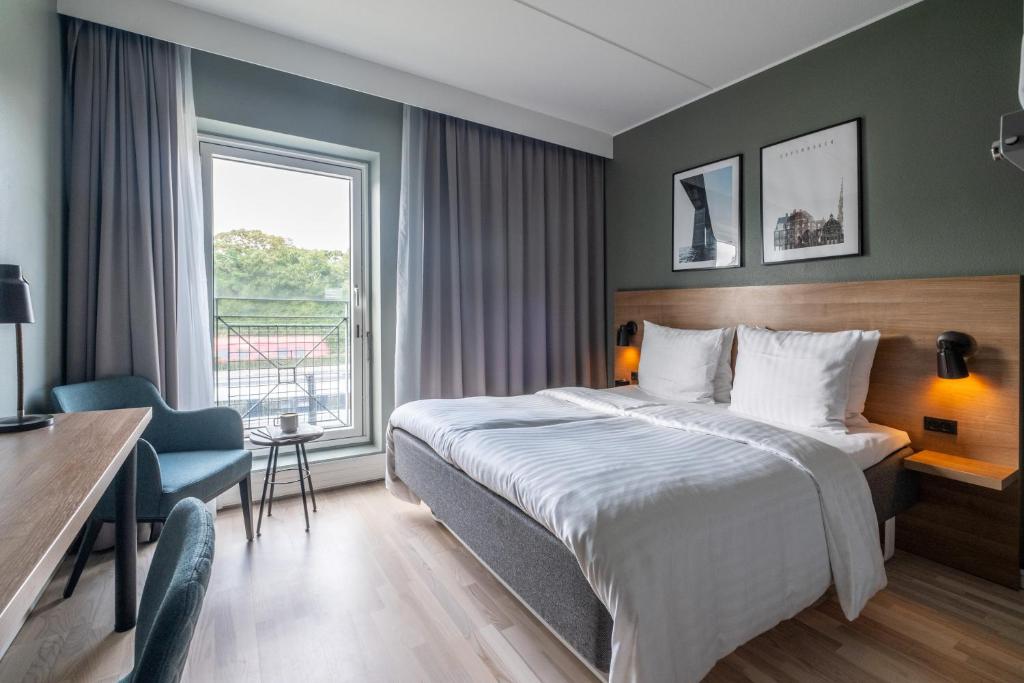 コペンハーゲンにあるGo Hotel Østerportのベッド、デスク、窓が備わるホテルルームです。