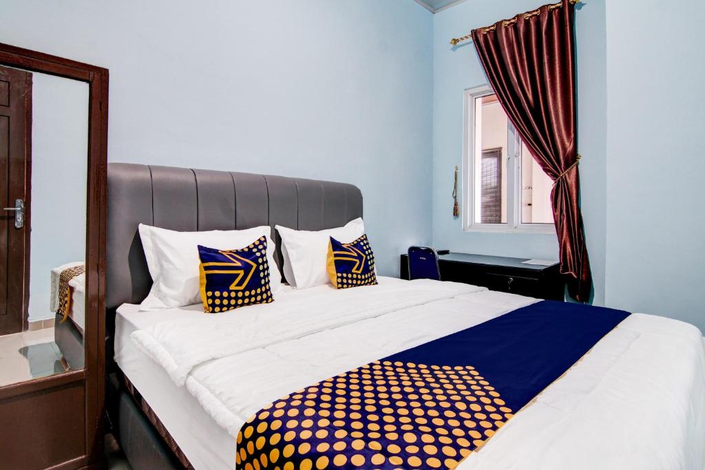 a bedroom with a bed with blue walls and a window at SPOT ON 92493 Pondok Mulia Syariah in Pekanbaru