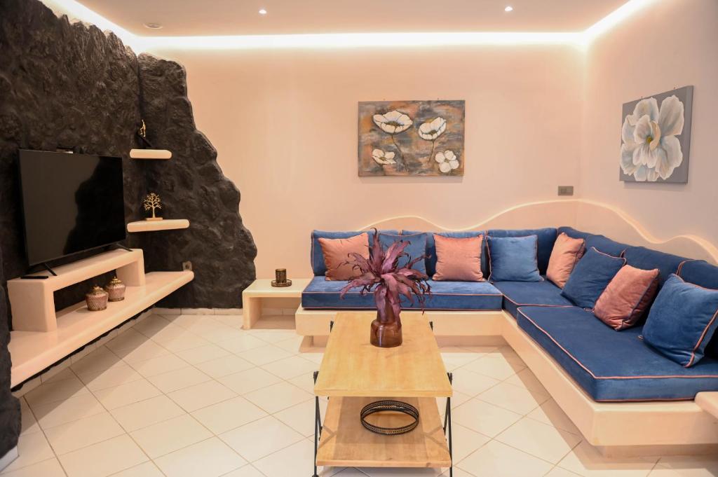 ein Wohnzimmer mit einem blauen Sofa und einem TV in der Unterkunft THE ROCK LUXURY HOMES in Mesariá