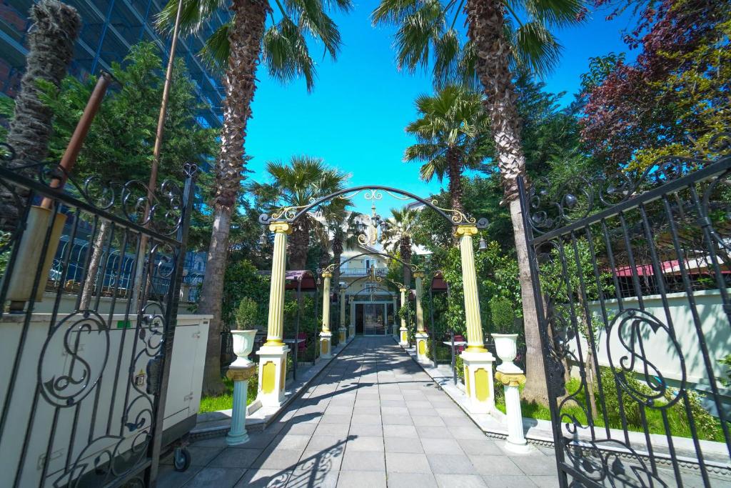 um portão na entrada de um resort com palmeiras em Olimpic Hotel em Tirana