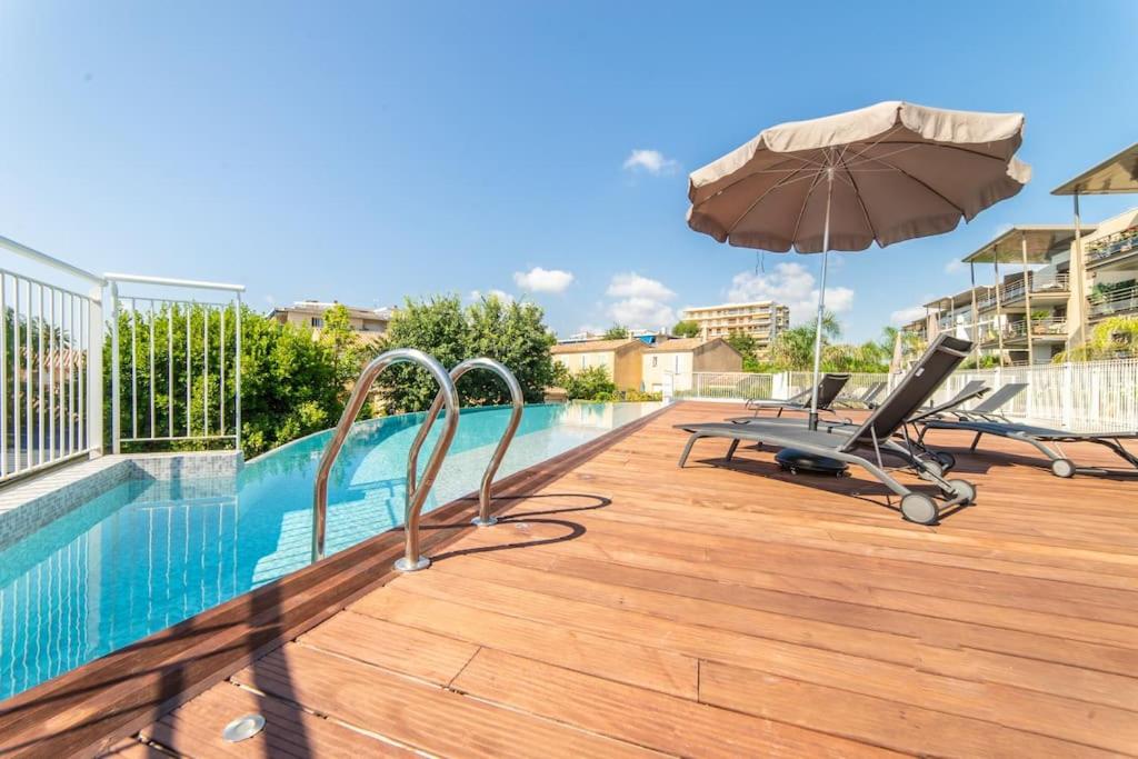 - une piscine avec une chaise et un parasol dans l'établissement A7- 2 bdr partial sea view AC parking terrace pool, à Antibes