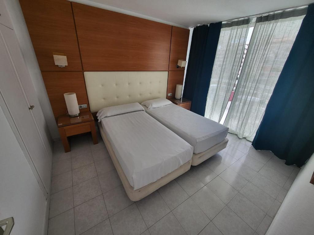 a bedroom with a large white bed and a table at Cozy Apartment near the beach in Playa de las Americas