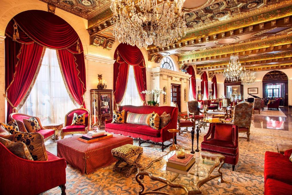 uma ampla sala de estar com mobiliário vermelho e um lustre em The St. Regis Washington, D.C. em Washington