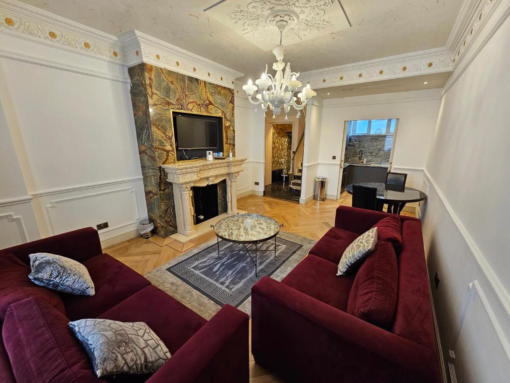 a living room with two red couches and a fireplace at Flat 1, Charles Street in London