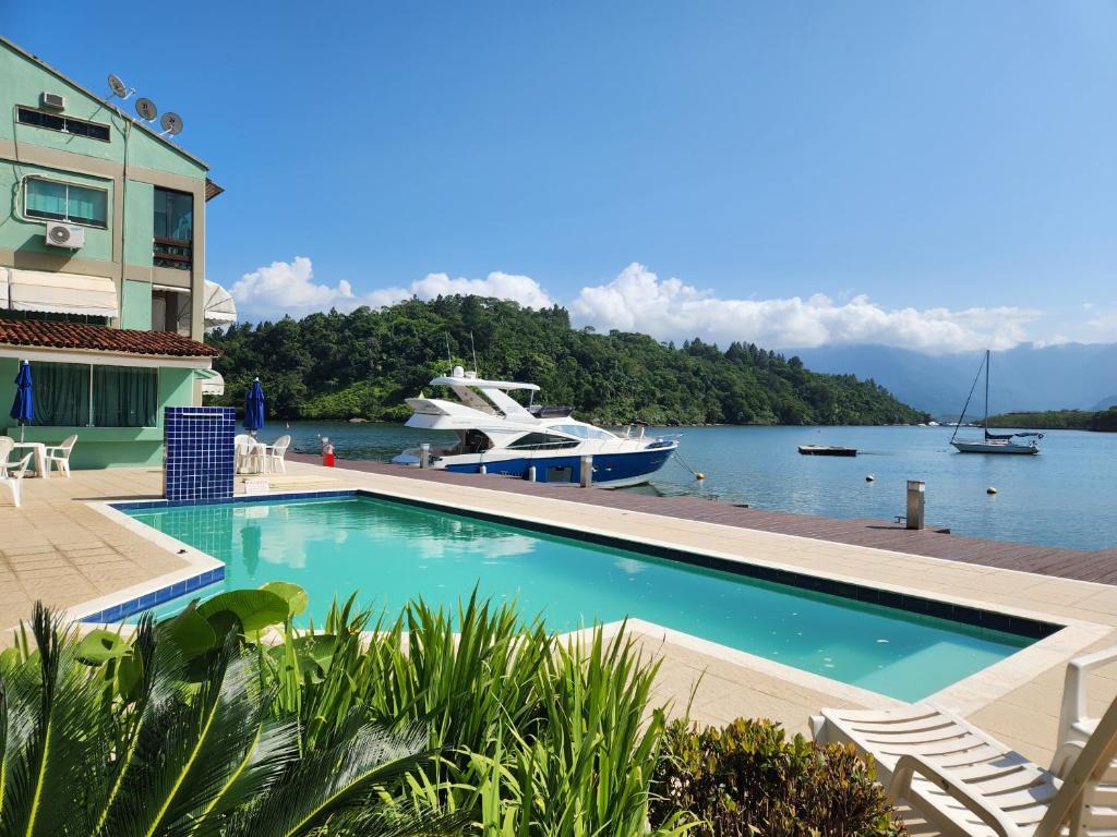 a swimming pool with a boat in the water at AP ALECRIM Luxo Cond Aquarius I Angra dos Reis in Angra dos Reis