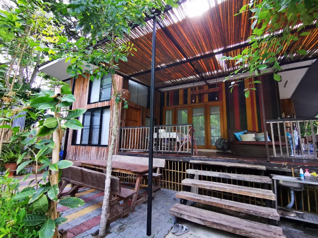 une terrasse couverte d'une maison avec un banc et des arbres dans l'établissement Brookhouse at Khaoyai, à Ban Khanong Phra Klang (1)