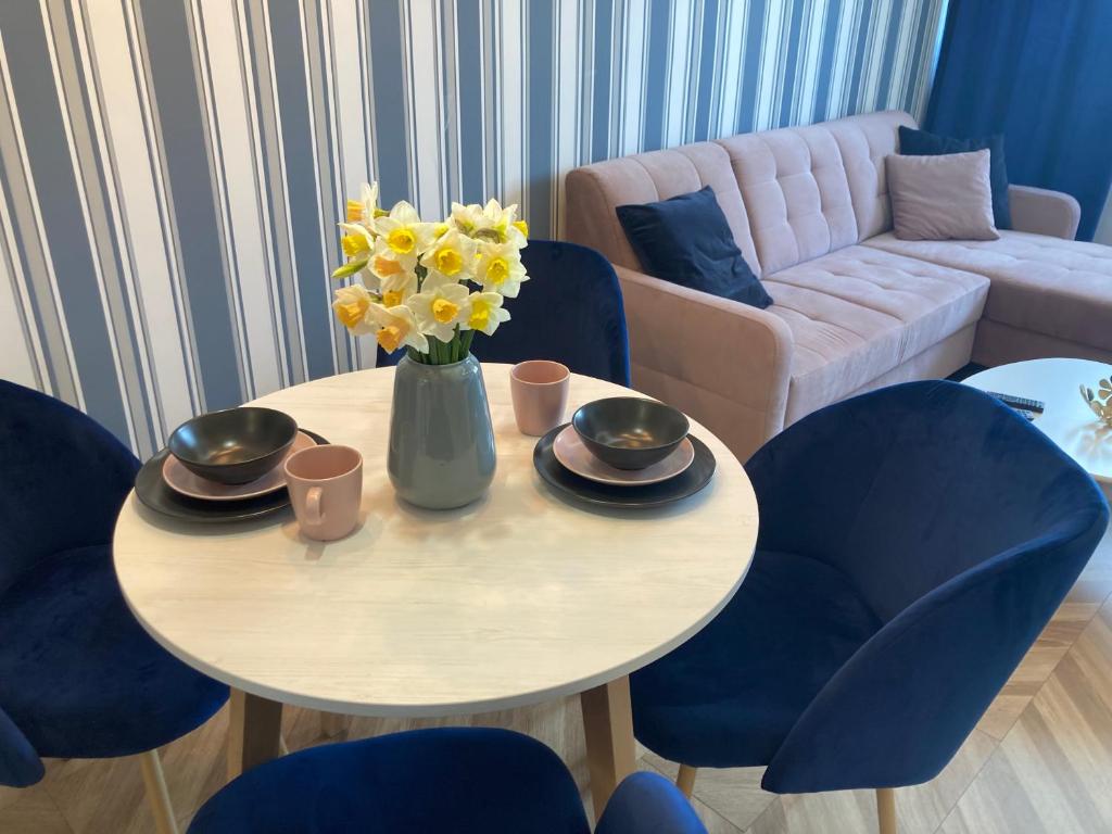 ein Wohnzimmer mit einem Tisch mit einer Vase gelber Blumen in der Unterkunft Tabago Studio 6 in Kattowitz