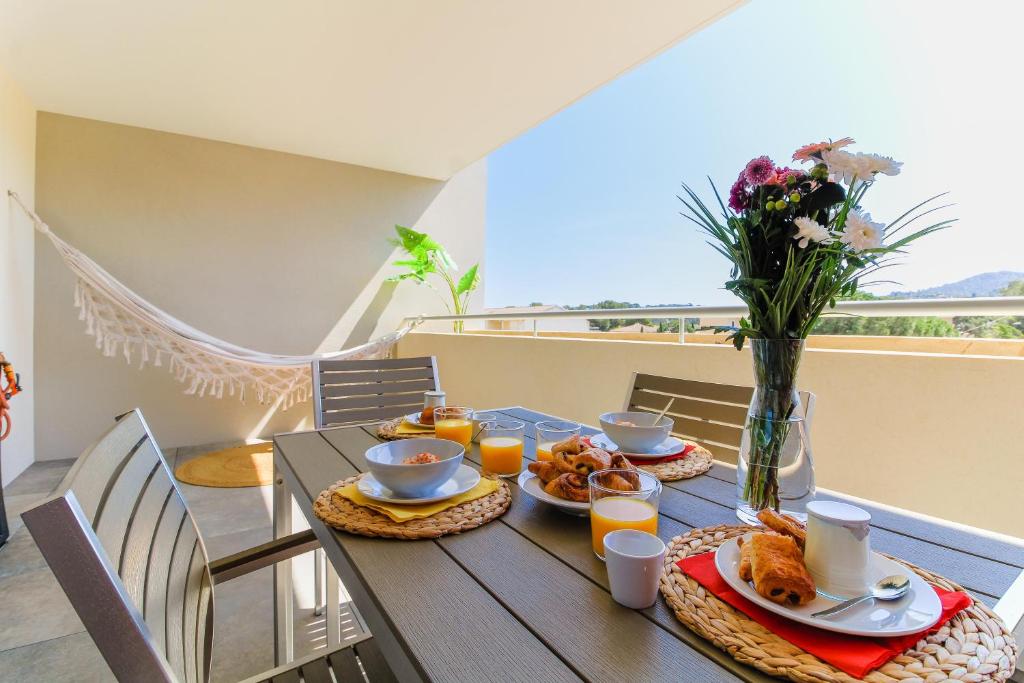 einen Tisch mit Frühstückszutaten auf dem Balkon in der Unterkunft SELECT SO HOME - Magnifique appartement dans une résidence avec piscine et à proximité des plages - POS35 in Bormes-les-Mimosas
