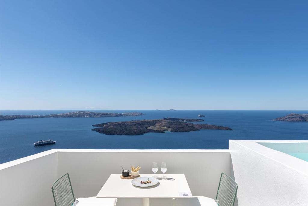 a white balcony with a table and chairs and the ocean at Akra Suites & Spa in Imerovigli