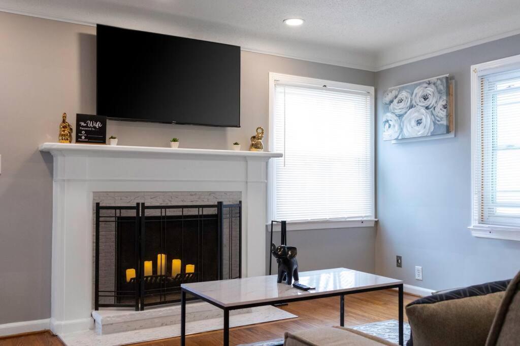 a living room with a fireplace with a tv above it at The Harperwood's Haven in Harper Woods