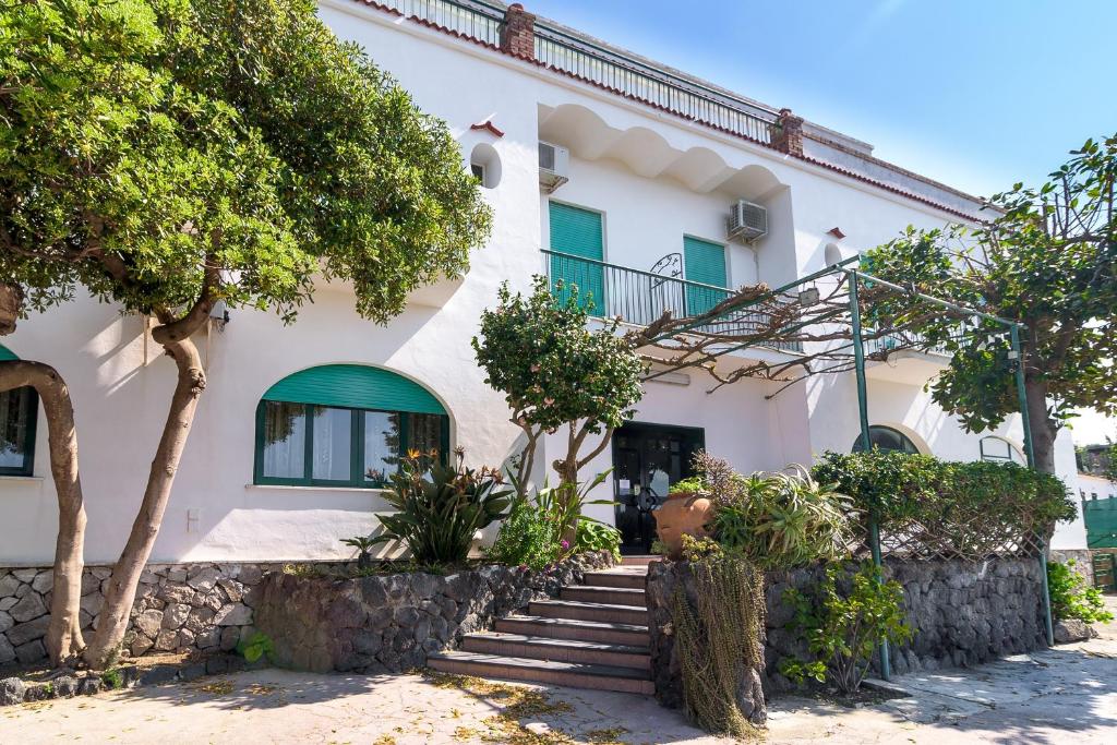 une maison blanche avec des arbres devant elle dans l'établissement Hotel Riviera, à Procida