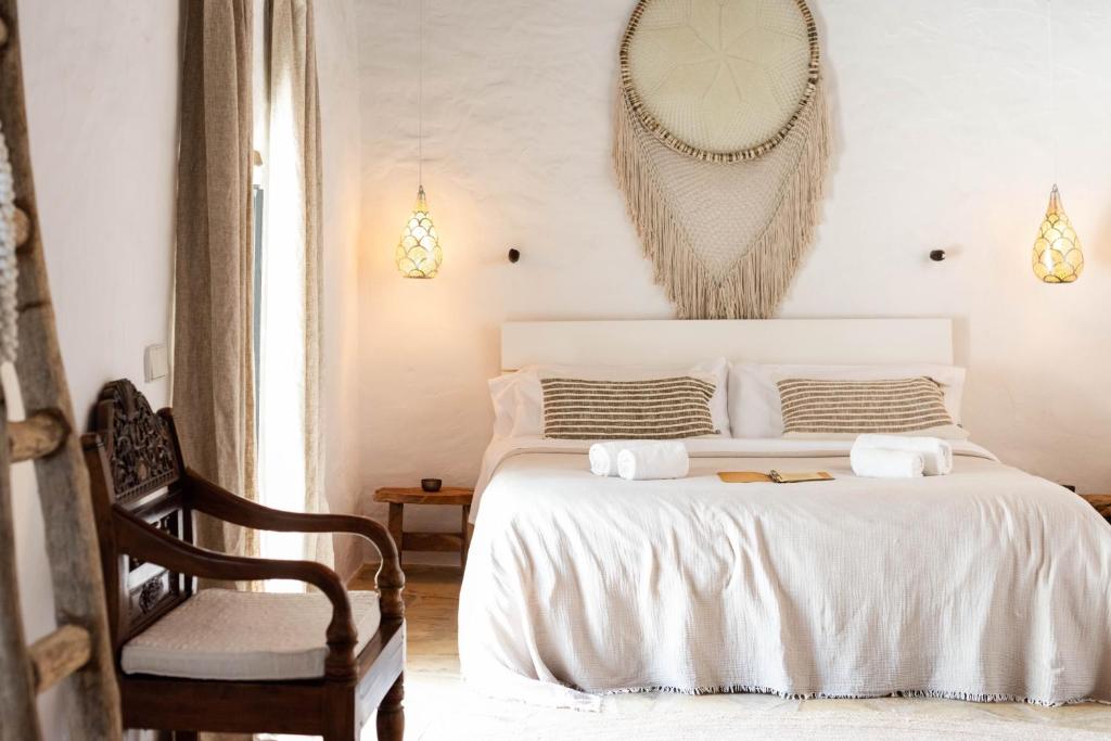 a white bedroom with a bed and a chair at Hotel Can Sastre in Santa Gertrudis de Fruitera