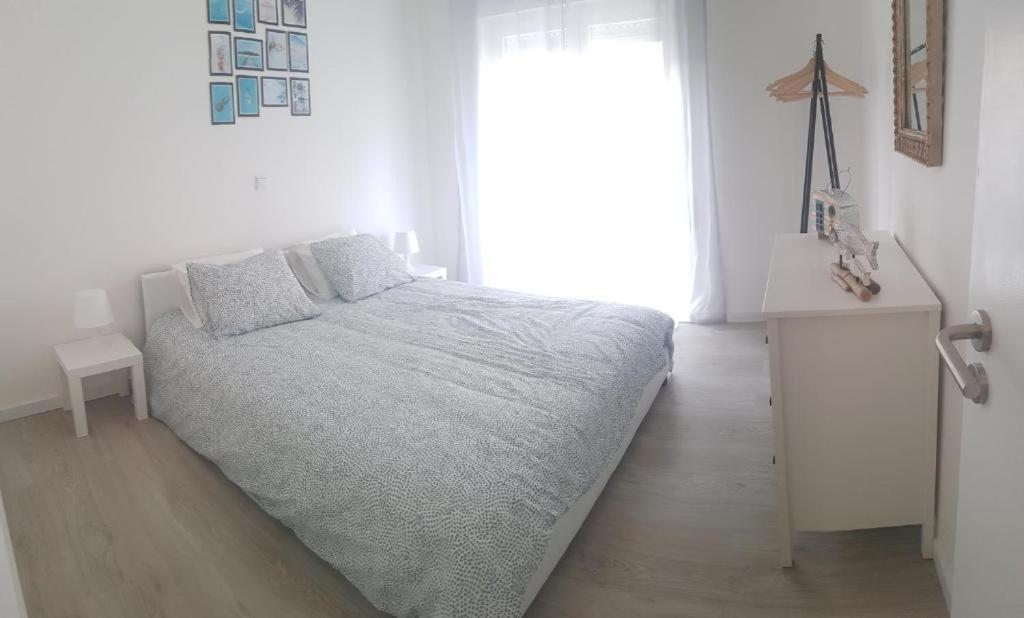 a white bedroom with a bed and a window at VieiraMar in Praia da Vieira