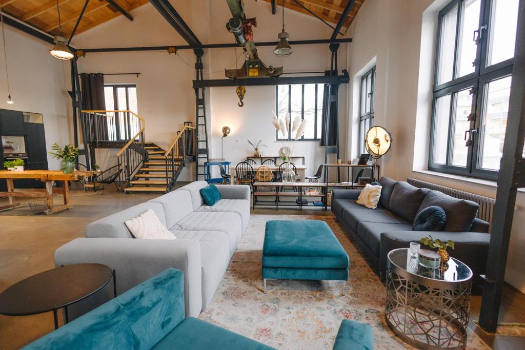 uma sala de estar com sofás, mesas e janelas em ElbQuartier Apartments Magdeburg 'Fabrik61' em Magdeburg