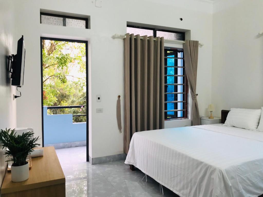 a bedroom with a white bed and a large window at Tam Coc Sunset Homestay in Ninh Binh