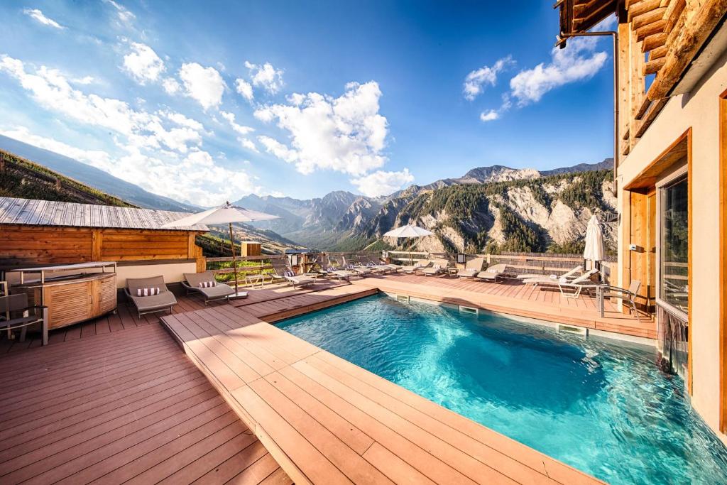 a swimming pool on a deck with a view of mountains at Hôtel & Spa L'Alta Peyra in Saint-Véran