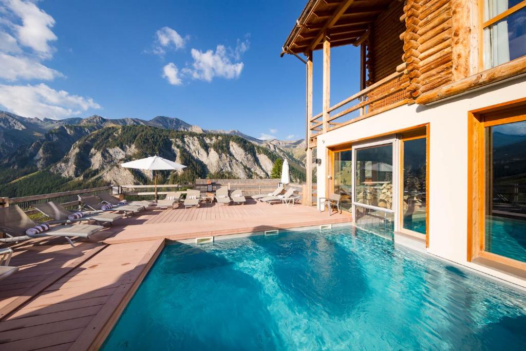 サン・ヴェランにあるHôtel & Spa L'Alta Peyraの山を背景にスイミングプールを併設する家
