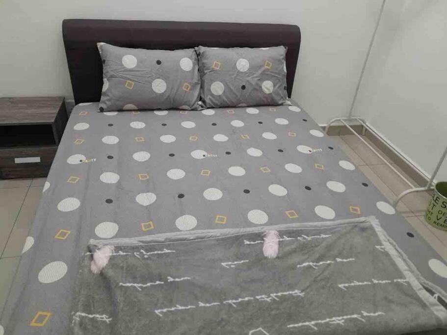 uma cama com lençóis de bolinhas e almofadas num quarto em Simple Home Taiping 简居 @ Suria Aman em Kamunting