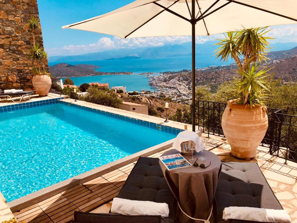 einen Pool mit einem Tisch und einem Sonnenschirm in der Unterkunft Villa Oleander in Elounda