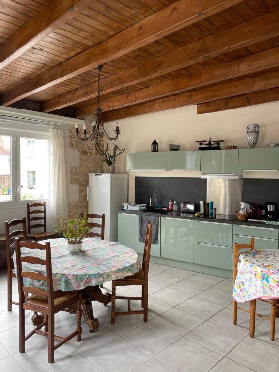 a kitchen with a table and chairs and a kitchen with green cabinets at Chez Sarah - L'Escapade in Javerlhac-et-la-Chapelle-Saint-Robert