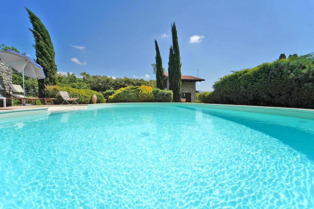 a large swimming pool with blue water at VILLA LE DUE LUNE 6 PAX , SWIMMING POOL, WI FI, TUSCAN STYLE in Filattiera