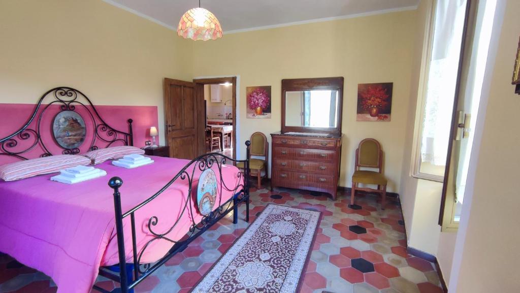 1 dormitorio con cama rosa y espejo en Ca Giulietto Antico Casale in Lunigiana en Pontremoli