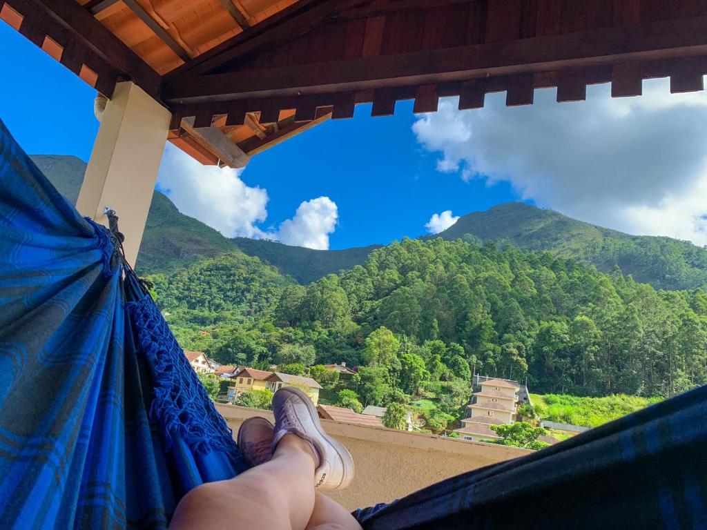 a person holding a hammock looking out at the mountains at Recanto dos Herdy´s in Nova Friburgo
