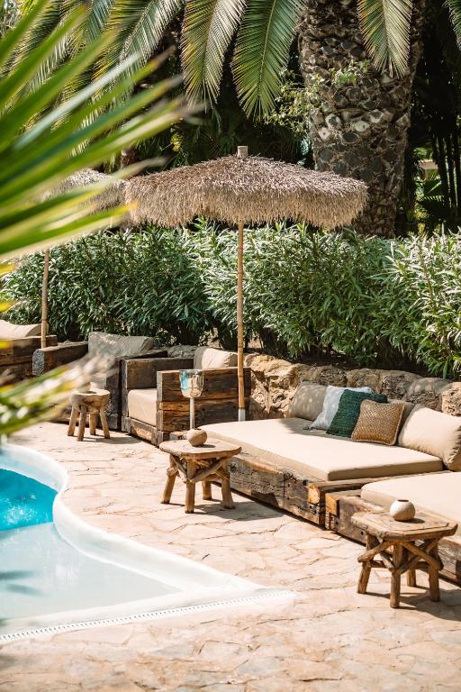 patio z kanapą i parasolem przy basenie w obiekcie Hotel Can Sastre w mieście Santa Gertrudis de Fruitera