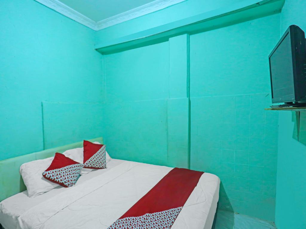 a blue room with a bed with pillows on it at OYO 92496 Faraas Homestay Syariah in Nongsa