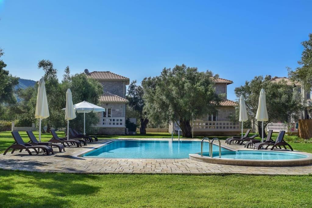 een zwembad met stoelen en parasols voor een huis bij Villa *Orizontas*/5' from town-sea/Mountain view in Lefkada