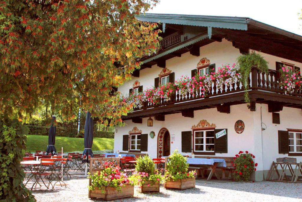 budynek ze stołami, krzesłami i kwiatami przed nim w obiekcie Pension Brucker w mieście Aschau im Chiemgau