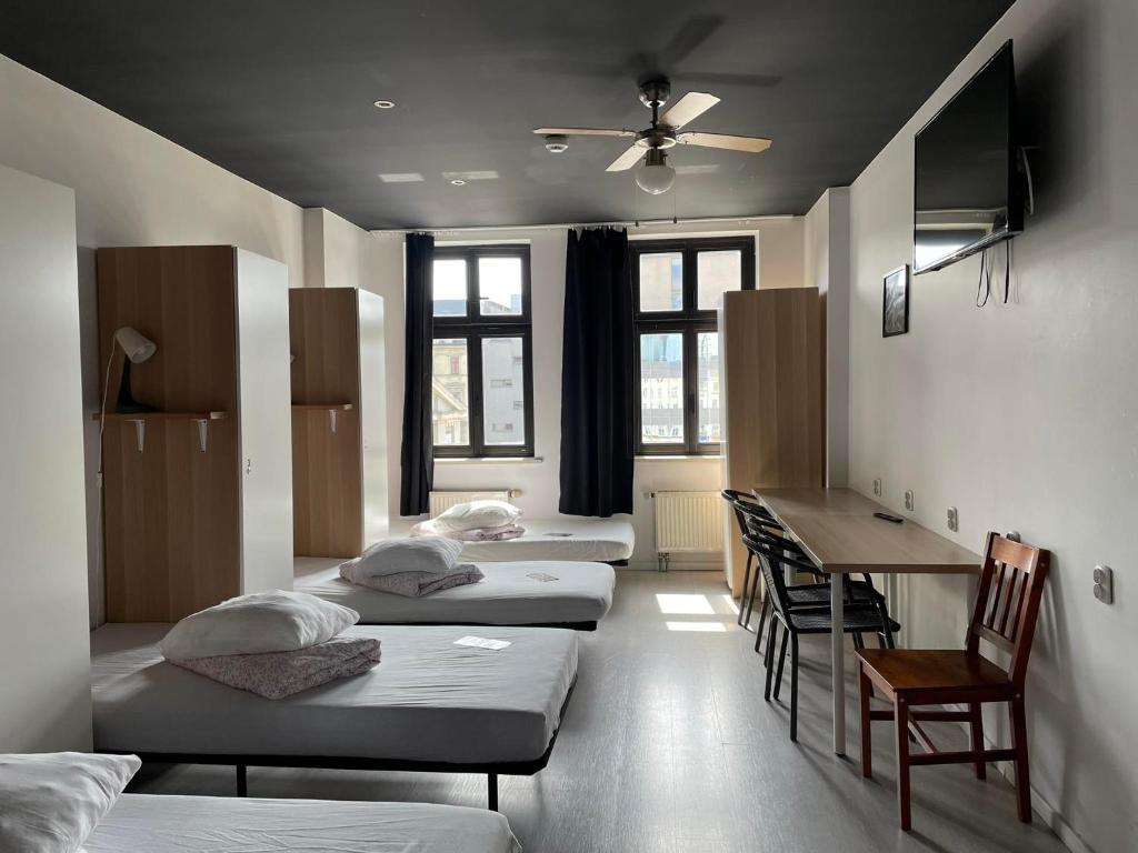 Cette chambre comprend 3 lits, une table et un bureau. dans l'établissement Hostel Kamienica Rynek 7, à Katowice