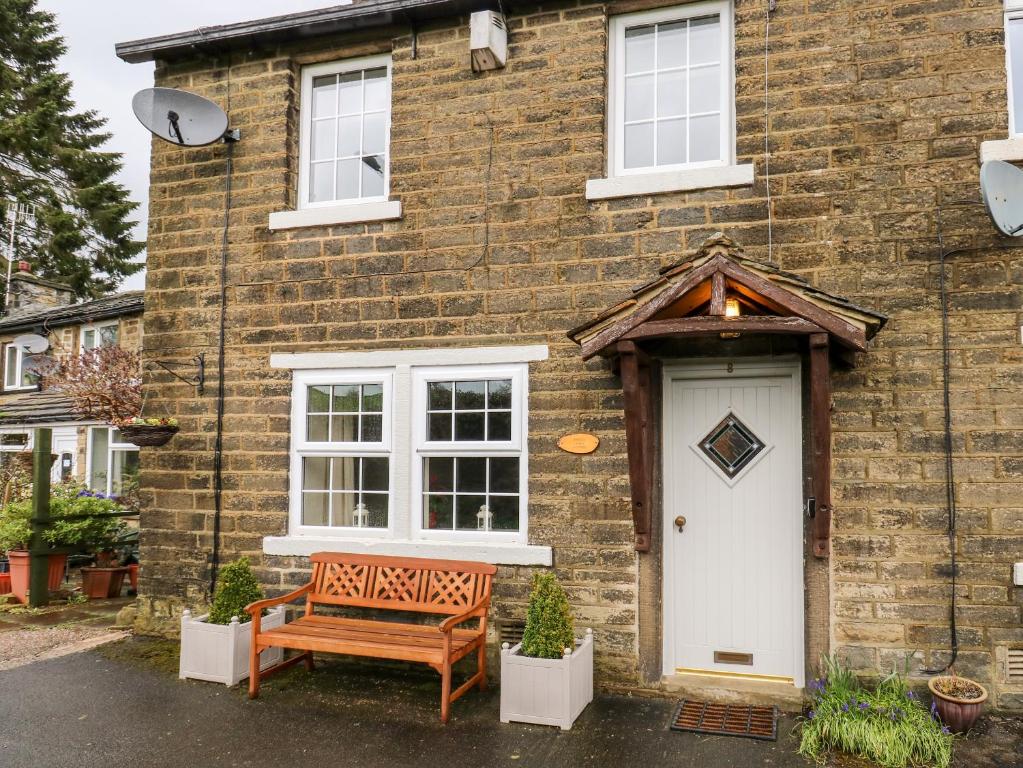 a wooden bench sitting outside of a brick house at Cherry Tree Cottage in Bingley