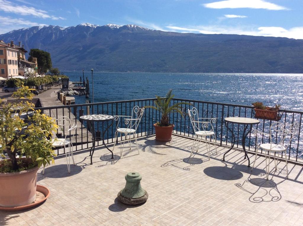 balcón con sillas, mesas y vistas al agua en Albergo Gargnano, en Gargnano