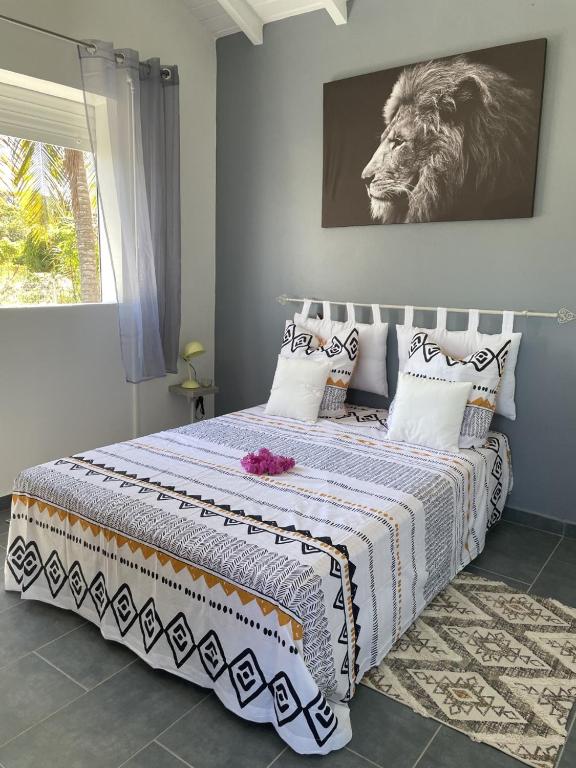 een slaapkamer met een bed met een leeuw aan de muur bij Bungalow de Rose in Petit-Canal