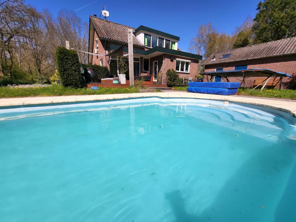 una gran piscina azul frente a una casa en Villa in the forrest of Amsterdam with Pool en Velsen-Zuid