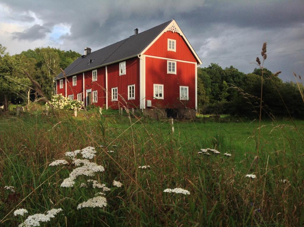 a red barn in the middle of a field at La Maison Rouge de Slätten Bed and Breakfast in Vilshult