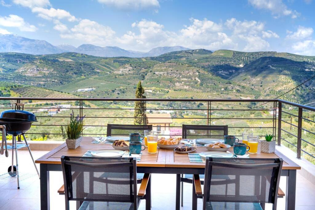 a wooden table with chairs on a balcony with mountains at Villa Penelope in Áyios Síllas