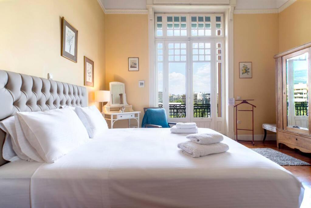 1 dormitorio con 1 cama blanca grande y toallas. en 1930's neoclassical apt in the heart of Athens, en Atenas