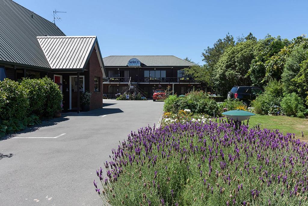 a garden with purple flowers in front of a building at Garden City Motel in Christchurch