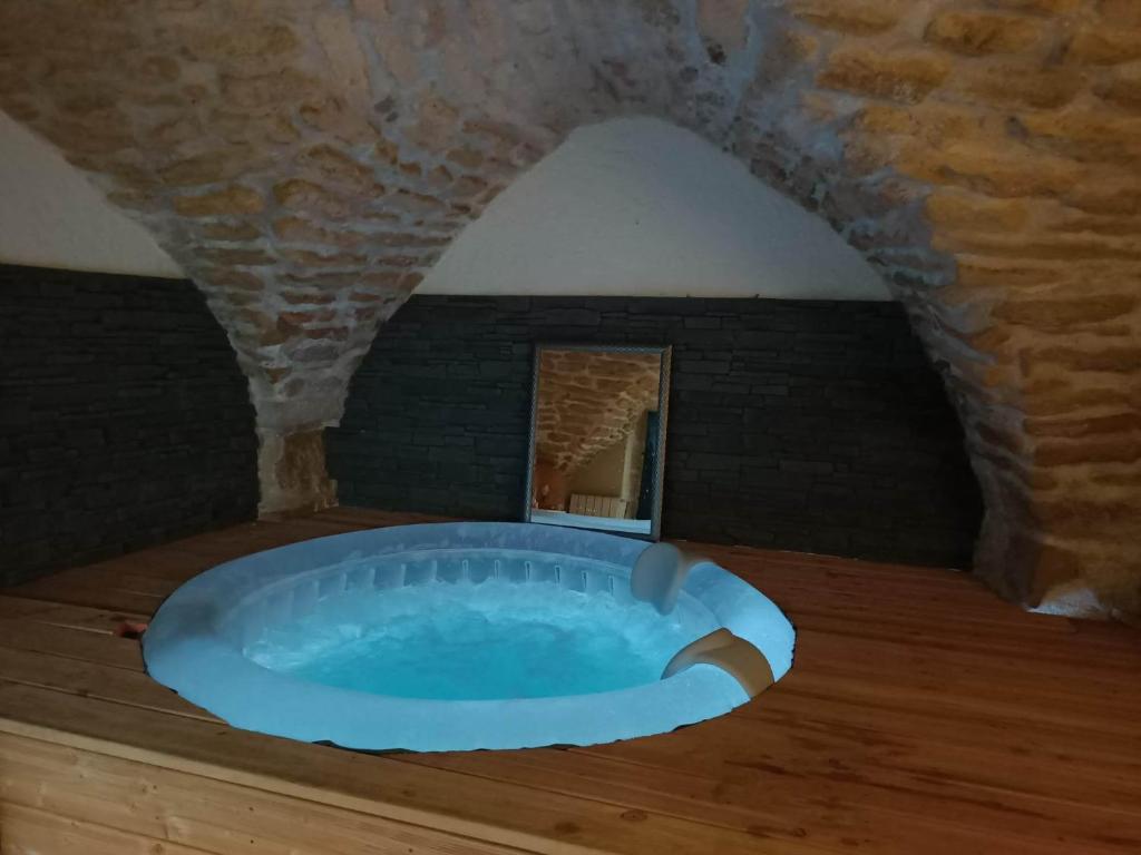 uma banheira de hidromassagem num quarto com uma parede de pedra em La Cachette em Aigues-Vives