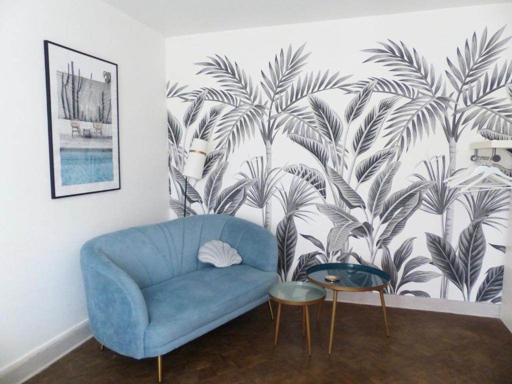 een blauwe bank in een woonkamer met palmbehang bij Bagatelle - 2 chambres in Talence
