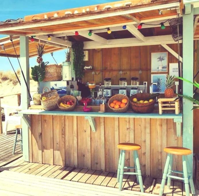 an outdoor bar with two stools and fruits on a deck at Mobil home Premium Camping 5* in Vendays-Montalivet